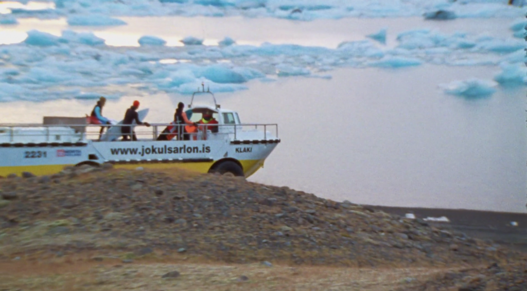 3人のサーファーがアイスランドの氷山の中サーフィン
